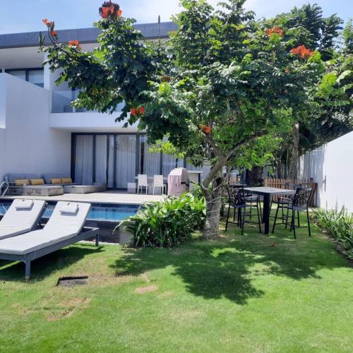 a garden with a table and a tree next to a pool at Villa 4 Phòng Ngủ Sanctuary Hồ Tràm - Cách Biển 70m in Ho Coc