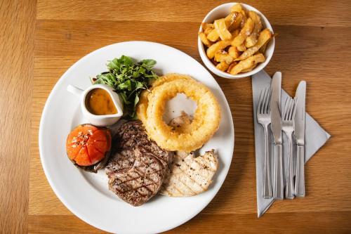 a plate of food with steak and onion rings and french fries at The Kellbank in Gosforth
