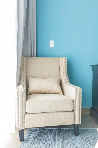 a chair in a room with a blue wall at Villa 4 Phòng Ngủ Sanctuary Hồ Tràm - Cách Biển 70m in Ho Coc