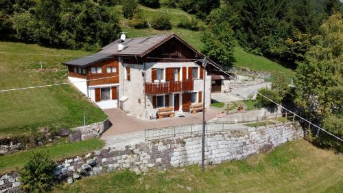 a house on a hill with a stone wall at Maso Patrizia - Rifugio caldo tra le vette in Pieve Tesino