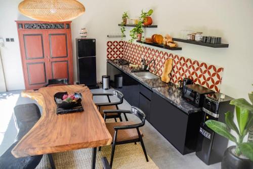 a kitchen with a wooden table and some chairs at Air Svarga Villa - Luxe Designer Villa Canggu in Canggu