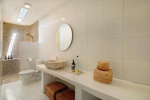 a bathroom with a sink and a toilet and a mirror at Villa Maison Pastis Canggu in Canggu