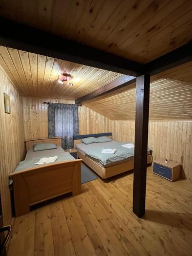 two beds in a room with wooden floors at Cabana Panga in Poiana Aiudului
