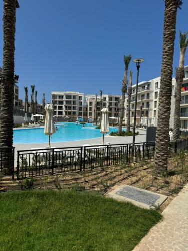 エル・アラメインにあるEmaar Marassi Garden viewの傘とヤシの木があるスイミングプール