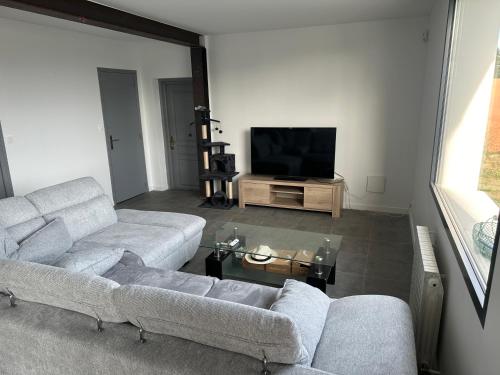 un salon avec deux canapés et une télévision à écran plat dans l'établissement Maison bord de mer, à Pleubian