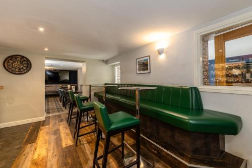 a bar with green seats and a table and chairs at The Kellbank in Gosforth