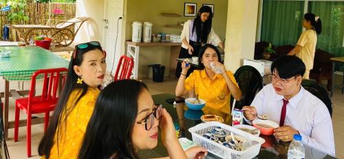a group of people sitting at a table eating food at Panutsaya Homestay in Wang Nam Khieo