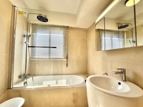 une salle de bain avec une baignoire, un lavabo et un miroir dans l'établissement Méditerranée by Welcome to Cannes, à Cannes