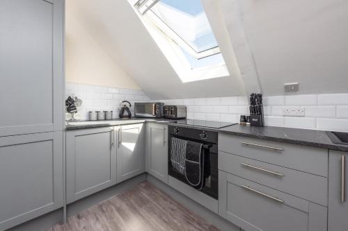 a kitchen with white cabinets and a skylight at Spacious City Centre 2 Bedroom Penthouse with Cathedral Views in Canterbury