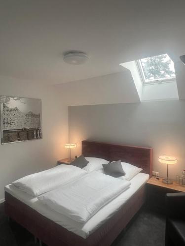 a bedroom with a bed with two lamps and a window at Pension Musa in Hamburg