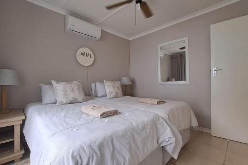 a bedroom with two beds and a clock on the wall at The Wooden Anchor spacious and modern in Zinkwazi Beach