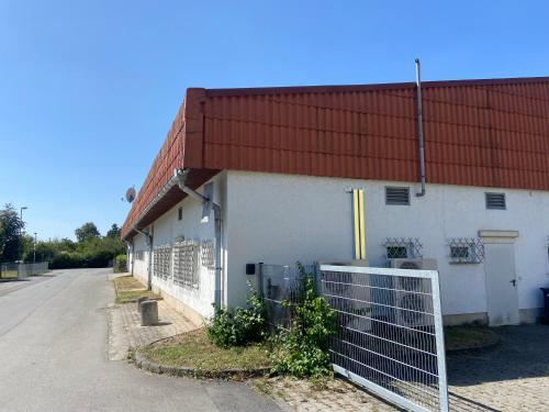 a white building with a red roof and a fence at Ferienwohnung Hainspitz Longstay in Hainspitz