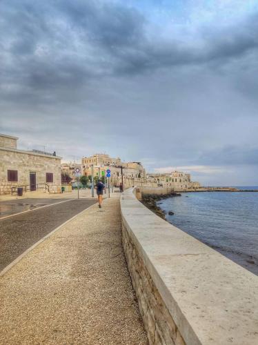 a person walking along a wall next to the water at Unique white stone Studio in Giovinazzo