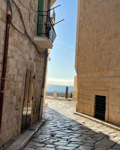 a stone alley with a door and a balcony on a building at Unique white stone Studio in Giovinazzo