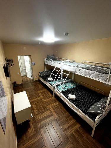 two bunk beds in a room with a wooden floor at Hostel 5 Сapsule Rooms in Ustʼ-Kamenogorsk