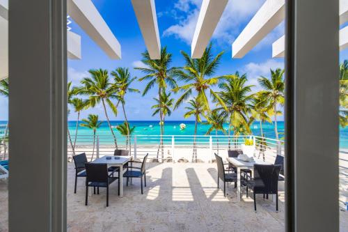 a restaurant on the beach with palm trees and the ocean at Dream Punta Cana Beachfront Apartment - 4-Bedroom Penthouse with Rooftop BBQ & Ocean Views in Punta Cana