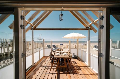 a dining table on a deck with a view of the beach at Thalassa Beach Houses in Zandvoort