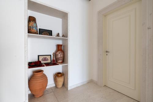 a room with a white wall with shelves with vases at Hotel Plaza Berat in Berat