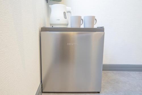 a small refrigerator with cups on top of it at Minutes from Sumiyoshi & Iconic Attractions & Sky Tree in Tokyo