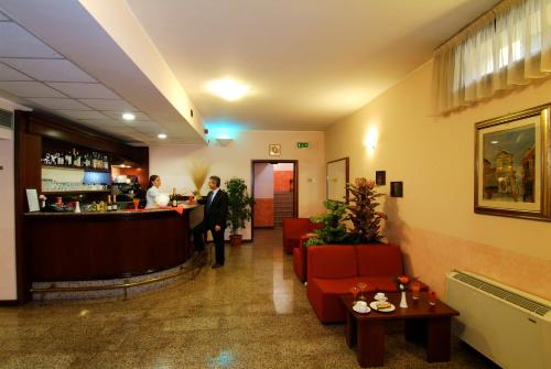 a lobby with a bar and people standing at a counter at Hotel Majestic in San Giuliano Milanese