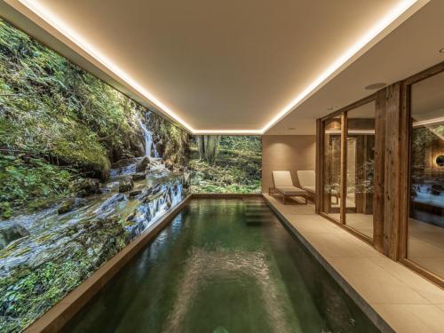 - une piscine à débordement dans une maison ornée d'une fresque murale représentant une cascade dans l'établissement Chalet de Luxe avec Piscine et Sauna, Proche des Pistes à Courchevel - FR-1-568-33, à Courchevel
