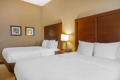 two beds in a hotel room with white sheets at Comfort Inn & Suites At CrossPlex Village in Birmingham