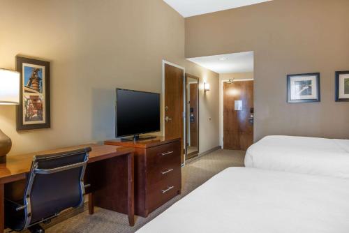a hotel room with a desk with a television and a bed at Comfort Inn & Suites At CrossPlex Village in Birmingham