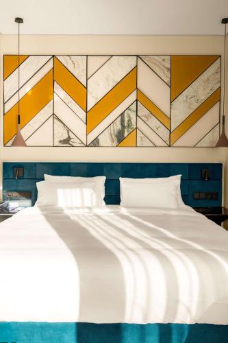 a bedroom with a white bed with a painting on the wall at Radisson Blu Aurum Hotel, Brasov in Braşov