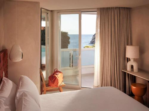 a hotel room with a bed and a view of the ocean at Mondrian Ibiza in Cala Llonga