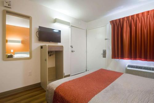 a bedroom with a bed and a mirror and a red curtain at Park Inn by Radisson, Lakewood in Lakewood