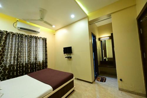 a bedroom with a bed and a tv and a window at Aasra Lodge in Ratnagiri