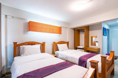 a bedroom with two beds and a mirror at XX GO INN Khaosan Road BKK - Grand Palace in Bangkok