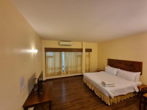a bedroom with a large white bed and a desk at Baan Lanna ChiangRai in Chiang Rai