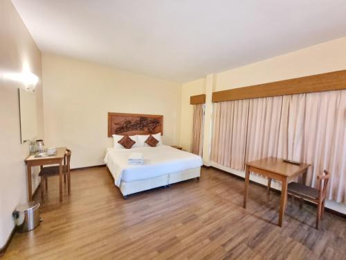 a hotel room with a bed and a desk and a table at Baan Lanna ChiangRai in Chiang Rai