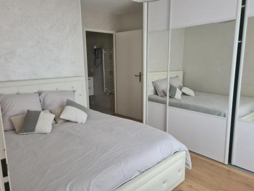 une chambre avec un lit blanc avec un miroir dans l'établissement Cosy appartement proche Paris, au Blanc-Mesnil