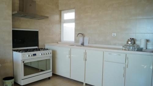 a kitchen with white cabinets and a stove and a window at Besan Motel in As Sulaymānīyah