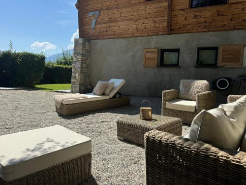 a patio with wicker furniture and chairs on gravel at Chalet 7 Luxury Chalet with Cinema room in Crans-Montana