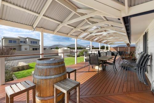 a deck with chairs and tables and a barrel at The Beach House in Middleton