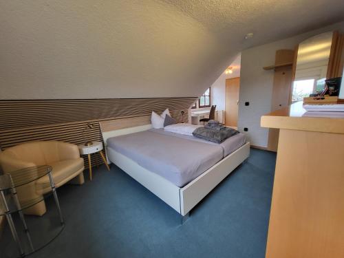 a bedroom with a bed and a chair in a room at Hotel Schönblick in Bad Herrenalb