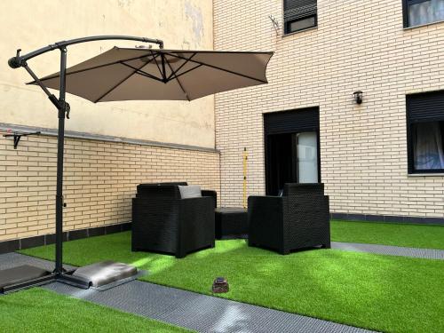 a patio with an umbrella and some green grass at El BC Zaragoza - Aljafería in Zaragoza