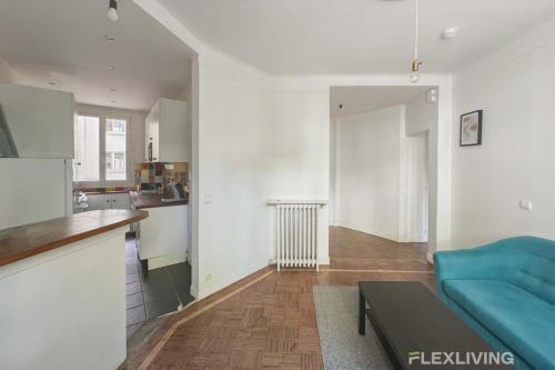 un salon avec un canapé bleu et une cuisine dans l'établissement Flexliving - whole flat - Verdun, à Paris