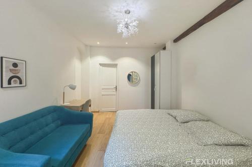 une chambre avec un lit et un canapé bleu dans l'établissement Flexliving - studio - Lemoine, à Paris