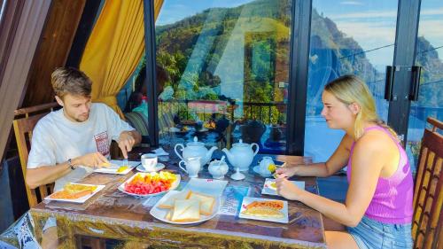 Ein Mann und eine Frau sitzen an einem Tisch und essen in der Unterkunft White Moon Cabin & Cottage in Ella