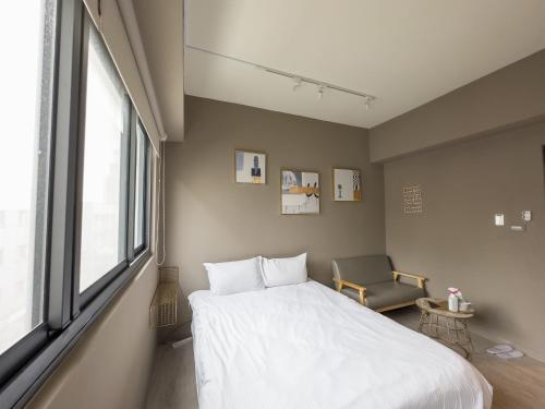 a bedroom with a large white bed and a chair at Febe旅日子 in Taichung