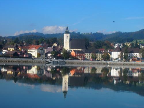 a town with a reflection in a body of water at Gasthof zur Donaubrücke in Ardagger Markt