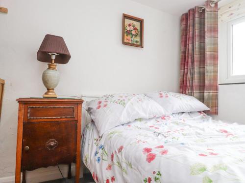 a bedroom with a bed and a lamp on a dresser at Quarry Cottage in Bangor