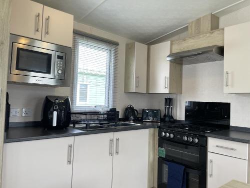 a kitchen with white cabinets and a microwave at The Thimble Static Holiday Home in Lancaster