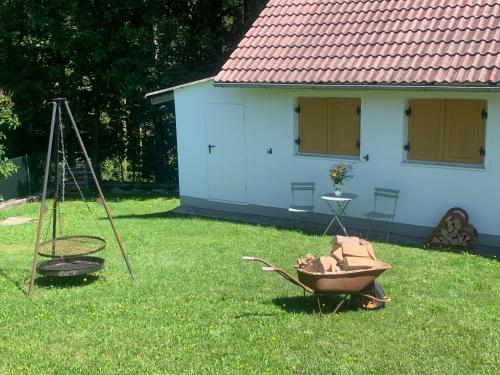 a yard with a house and a wheelbarrow in the grass at Auszeit 2 0 Digital Detox in Obergrünburg