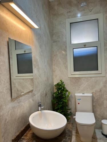 a bathroom with a sink and a toilet and two windows at Modern 2-Bedroom Apartment in Cairo