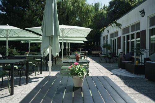 a patio with tables and chairs and an umbrella at Seminaris Hotel Potsdam Griebnitzsee in Potsdam